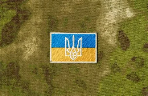 Patch with the flag and coat of arms of Ukraine, on a camouflage background. Stock Photos
