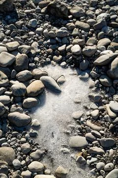 Patch of frozen water between white stones Stock Photos