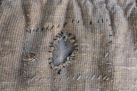Patch roughly sewn within on a torn coarse sackcloth, background 스톡 사진