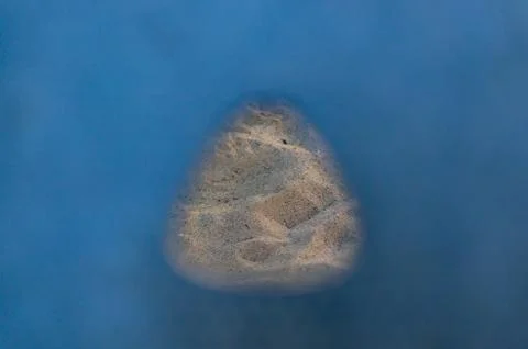 Patch of sand visible through a hole on a blue surface Stock Photos