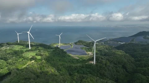 Patch of sun moves over wind turbines and solar panels on coastal hillside Vídeos de archivo 200978720