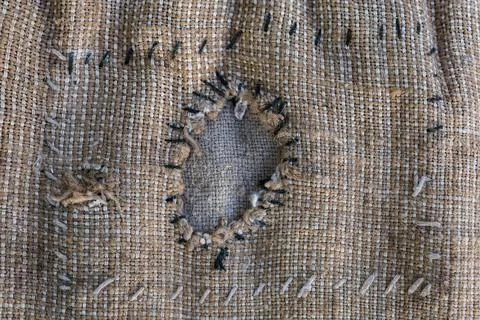Patch on torn coarse sackcloth roughly sewn within, close-up Fotos de archivo