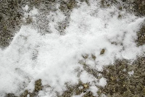 A patch of white snow on a granite surface. Stock Photos