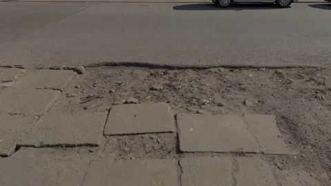 Patched road surface with passing vehicle visible at top, depressed paving Stock Footage 333908319