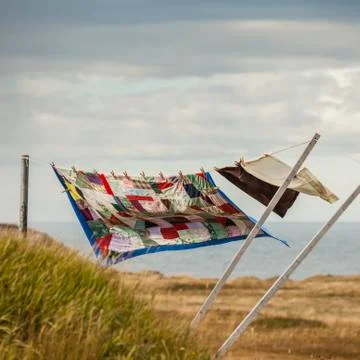 A patchwork blanket and pillow cases hanging on a clothesline with the Atlantic Fotos de archivo