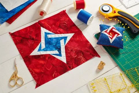 Patchwork block, pin cushion and quilting accessories on white wooden surface Stock Photos