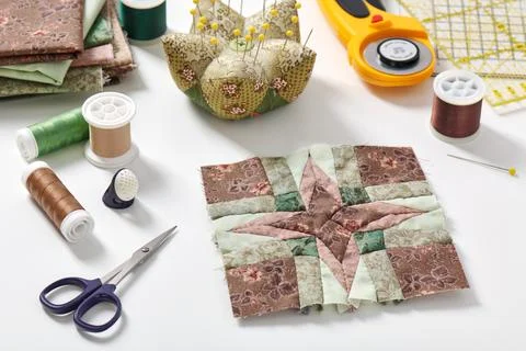 Patchwork block, stack of fabrics, pincushion, sewing and quilting accessories 스톡 사진