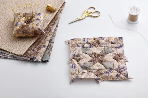 Patchwork block, stack of fabrics, sewing and quilting accessories. Fotos de archivo