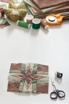 Patchwork block, stack of fabrics, sewing and quilting accessories. Copy space Stock-Fotos