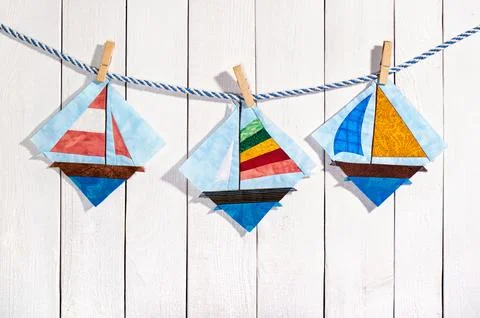 Patchwork blocks attached with clothespins on a rope on a white wooden back.. 库存照片