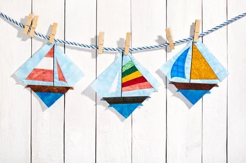 Patchwork blocks attached with clothespins on a rope on a white wooden back.. Stock-Fotos