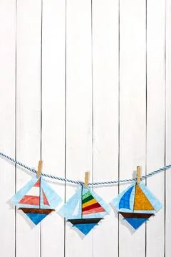 Patchwork blocks attached with clothespins on a rope on a white wooden back.. Stock Photos