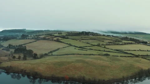 Patchwork farm fields and hedgerows by a lake in Ireland aerial Video stock 154811904