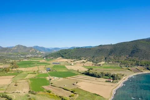 Patchwork farmland and coastline under blue sky Stock Photos