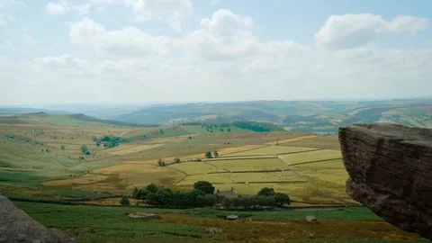 Patchwork farmland beneath dramatic sky with rugged granite outcrop. Rolling Stock Footage 342806362