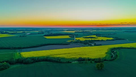 Patchwork farmland with green and yellow fields at dusk under colorful sky Stock Footage 312189070