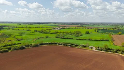 Patchwork farmland with pasture, plowed soil, and hedgerow boundaries from drone 動画素材 339342507