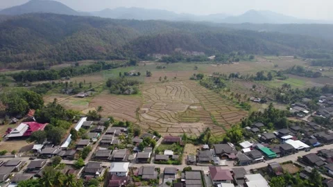 Patchwork fields surrounded by village houses and foggy mountain range. Stock Footage 246658796
