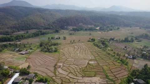 Patchwork fields surrounded by village houses and foggy mountain range. Video stock 246658810