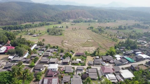 Patchwork fields surrounded by village houses and foggy mountain range. Video stock 246658994