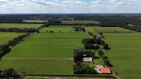 Patchwork green pastures spread around white farmhouse with red barn in rural Stock Footage 346350436