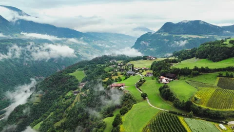 Patchwork meadows and hillside farms across a Dolomite valley, aerial view Stock Footage 319909338