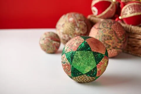 Patchwork puzzle balls and christmas decorations in basket on white and red.. Stock-Fotos