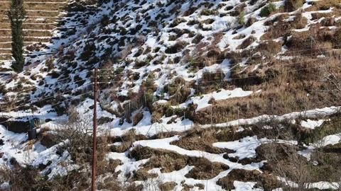 Patchy snow on terraced hillside fields during late winter season Stock Footage 328707266