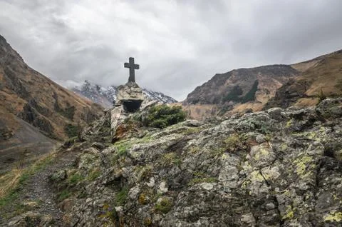 Path to ancient medieval monument in mountains of Caucasus. Christian cross i Stock Photos