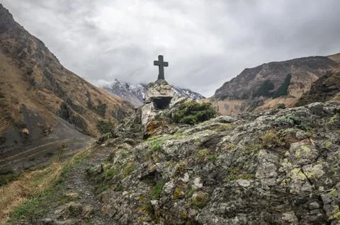 Path to ancient medieval monument in mountains of Caucasus. Christian cross i Stock Photos