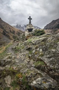 Path to ancient medieval monument in mountains of Caucasus. Christian cross i Stock Photos