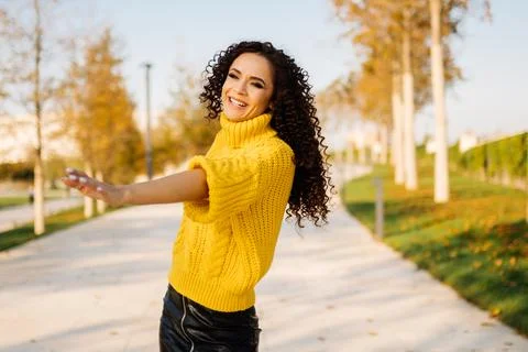 On the path of autumn park in a bright thick warm sweater whirling girl with Stock Photos