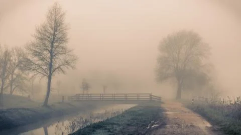 A path besides the river across the trees and the fog in Sils wetland in Giro Stock Photos