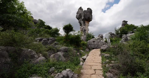 From path camera tilt up to show remarkable balancing top-heavy rock Stock Footage 329489986