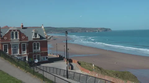 Path from cliff top to beach, passing red brick and sandstone Victorian hotel, Stock Footage 2924065