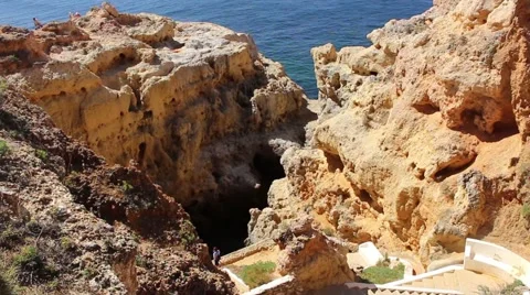 Path down craggy cliffs leading towards an inlet from the sea at the bottom Stock Footage 64959374