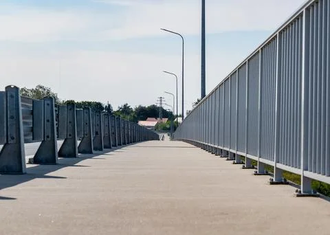 Path going along road fenced with railings and grid Фото