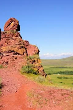 A path going along the top of the hill to an unusual red stone formation in a Stock Photos