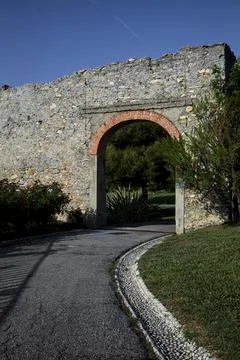 Path  going through an arch of an ancient bounday wall in a park Stock Photos