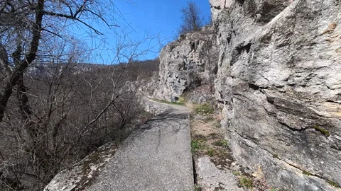 Path hugs steep cliffside under clear blue sky. Balkan, Eastern Europe, POV Video stock 331430358