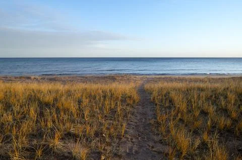 Path leading towards calm empty, peaceful lake Foto stock