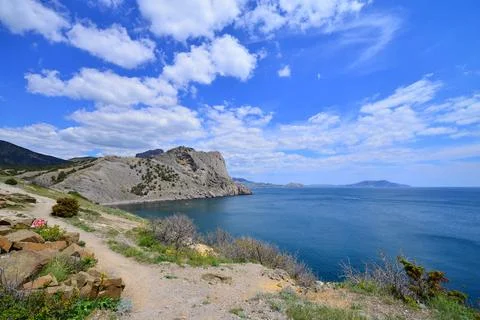 A path leads to a stunning cliff overlooking the vast sea Stock Photos