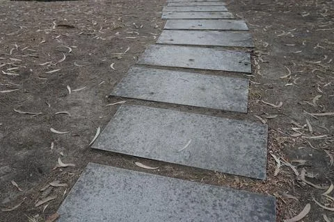 Path made of rectangular stones on the soil with fallen leaves 스톡 사진