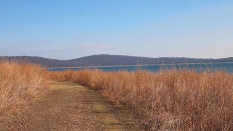Path in the middle of dry grass, with mountains in the distance Stock Footage 123284850