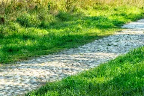 Path or sidewalk made with rock blocks near lawn. straight pathway in the mid Stock Photos
