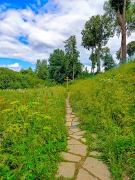 A path paved with stone in the grass leads to the Orthodox cross Stock Photos