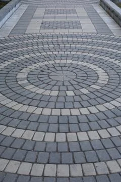 The path is paved with two shades of gray stone. Round pattern on a paved pat Stock Photos
