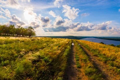 Path of relaxation. Dirt road parallel with big river Stock Photos