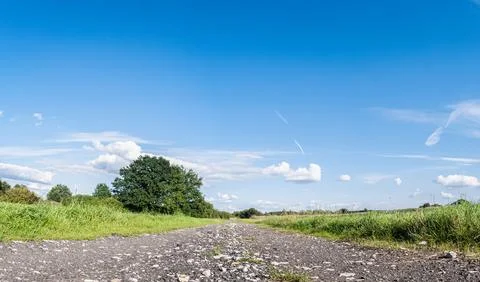 Path in rural landscape going through field areas under clouds Stockfoto's