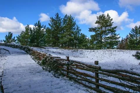 The path to the sea in the dunes is covered with a thin layer of snow. Stock Photos